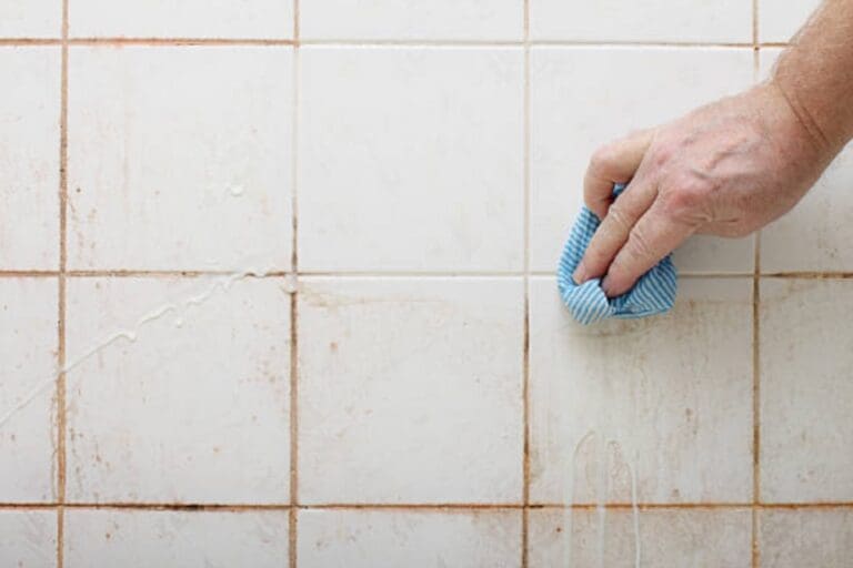 a person is cleaning grout with sponge.