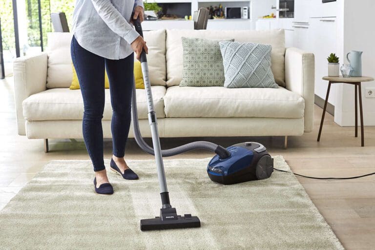 a person is vacuuming area rug on hardwood floor.