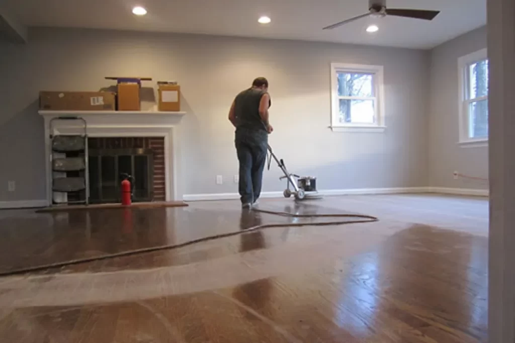 a professional floor cleaner is buffing hardwood floor with buffer machine.