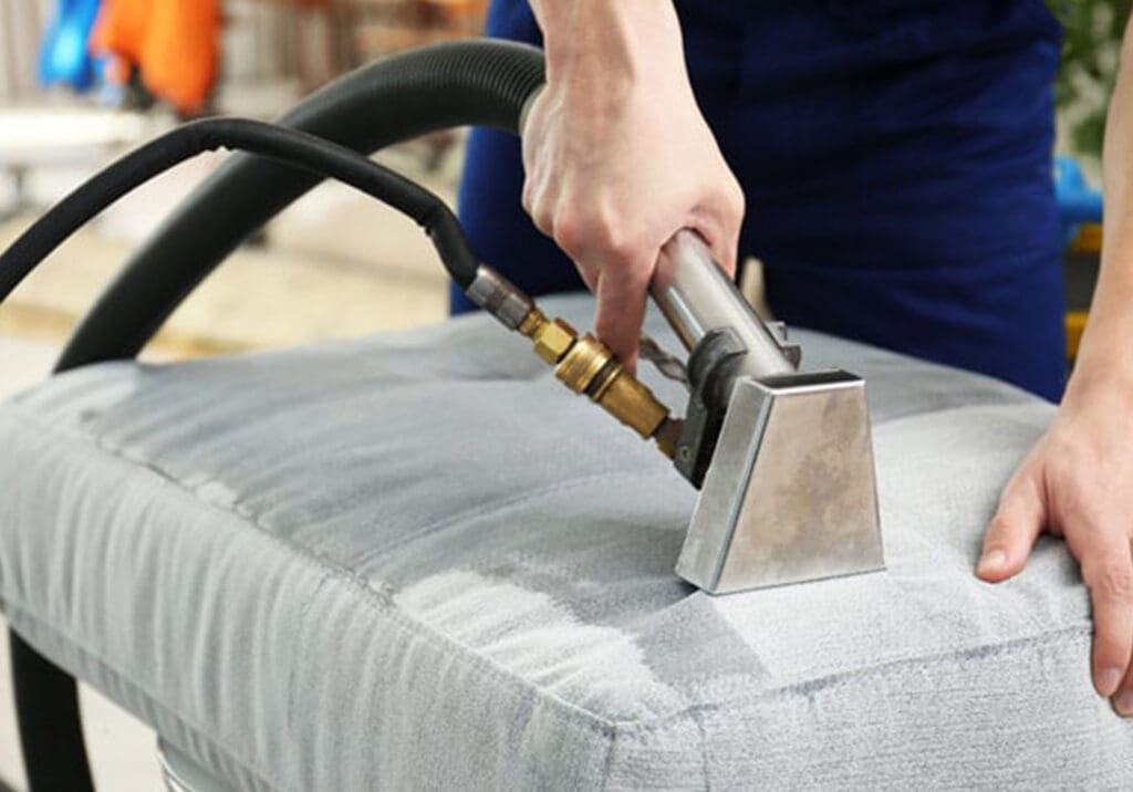 close shot of a vacuum cleaner in hand, cleaning sofa seat.