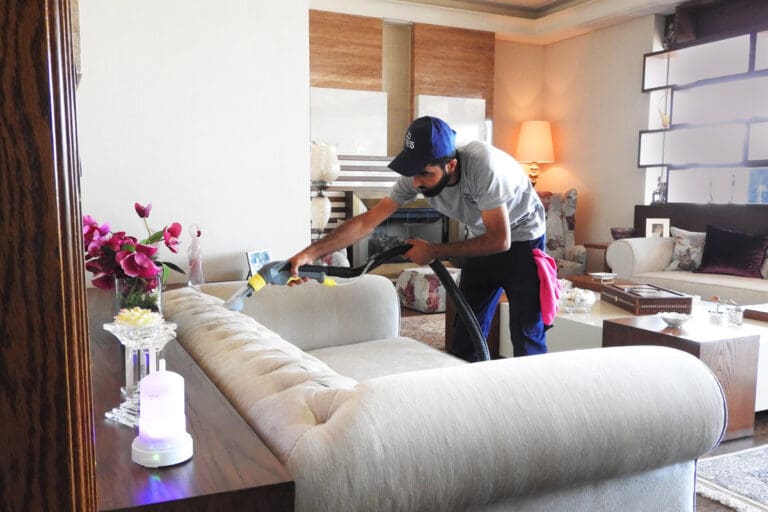an upholstery cleaning expert cleaning sofa with a vacuum cleaner in a house.