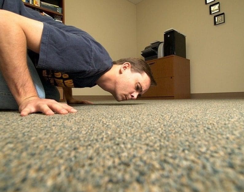 a person sniffing carpet on floor.