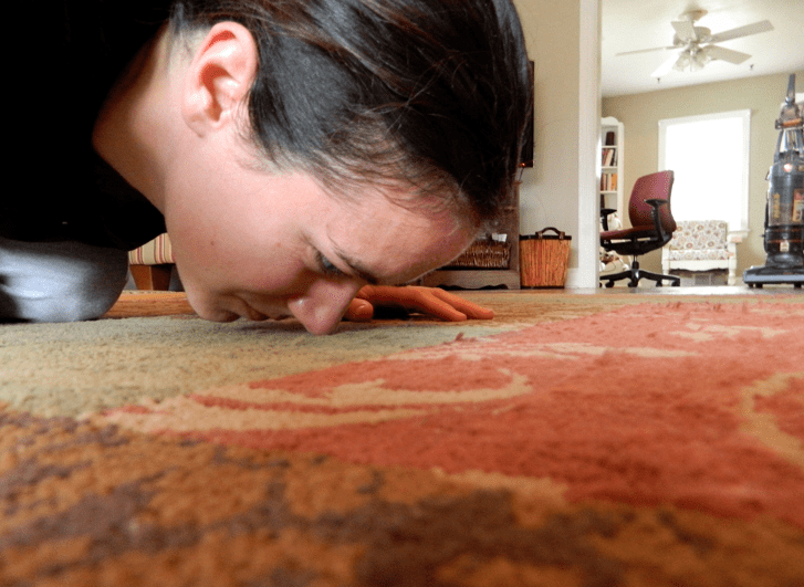 close shot of a woman face sniffing carpet.