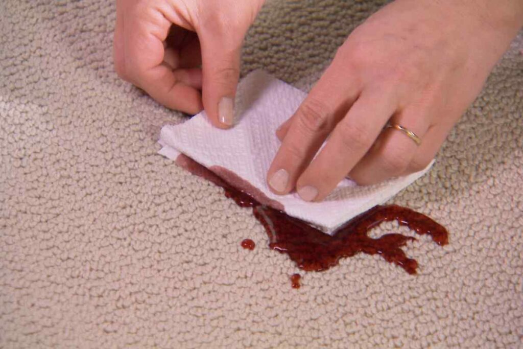 soaking up oil stain from carpet with tissue paper.